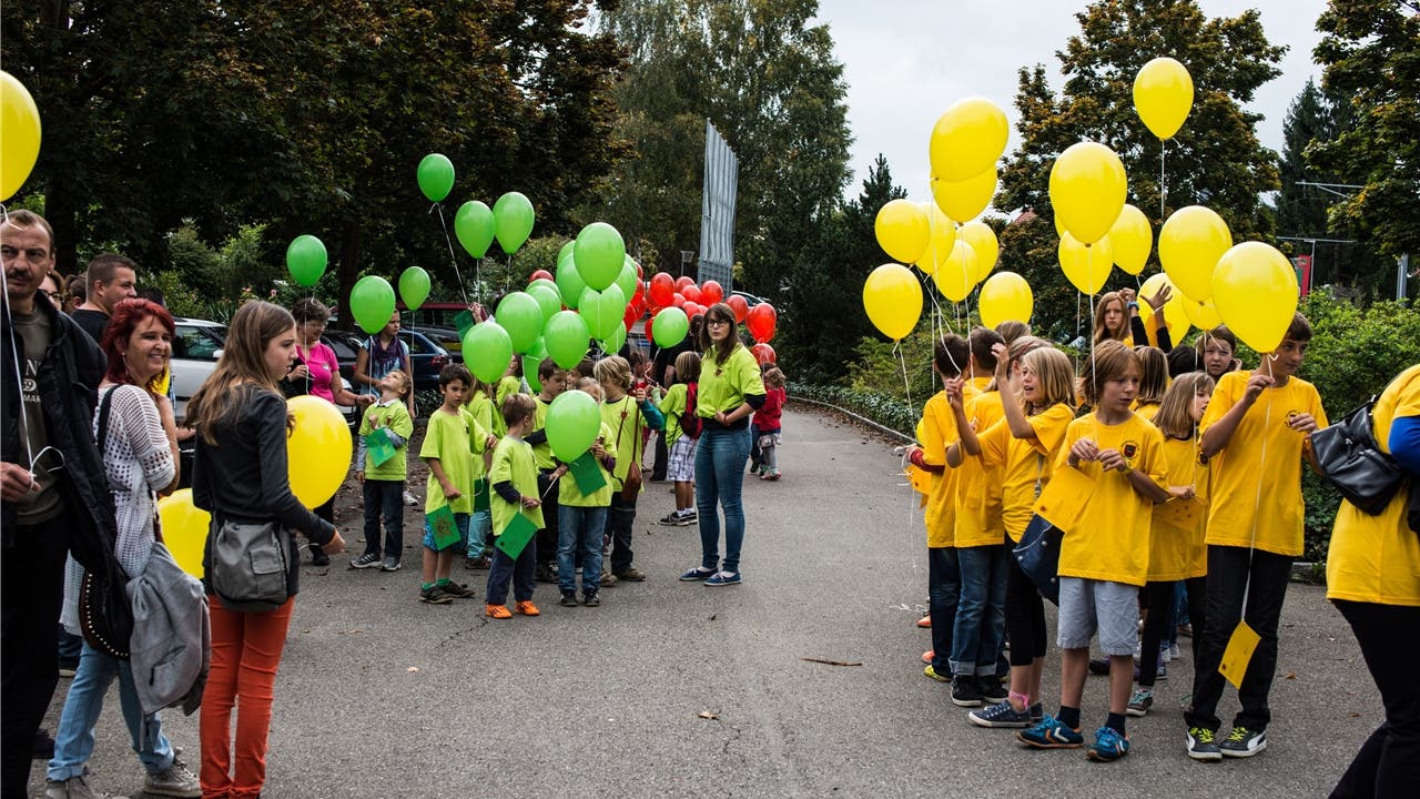Die Hallwiler Schüler befestigen ihre guten Wünsche an Luftballone in den Farben des Gemeindewappens.