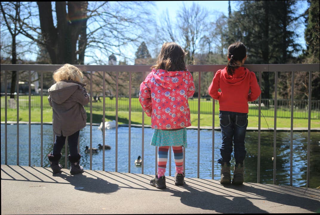 Kinder vergnügen sich am Teich des Kurparks. Zum Spiel halten sie einen Stecken als Fischerute ins Wasser. Ob die Enten wohl bei diesem Wetter beissen?
