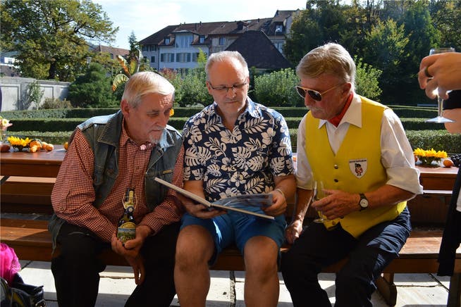 Manfred Lässig senior, Manfred Lässig junior und Gusti Beer (von links) ganz vertieft ins Jubiläumsbuch.