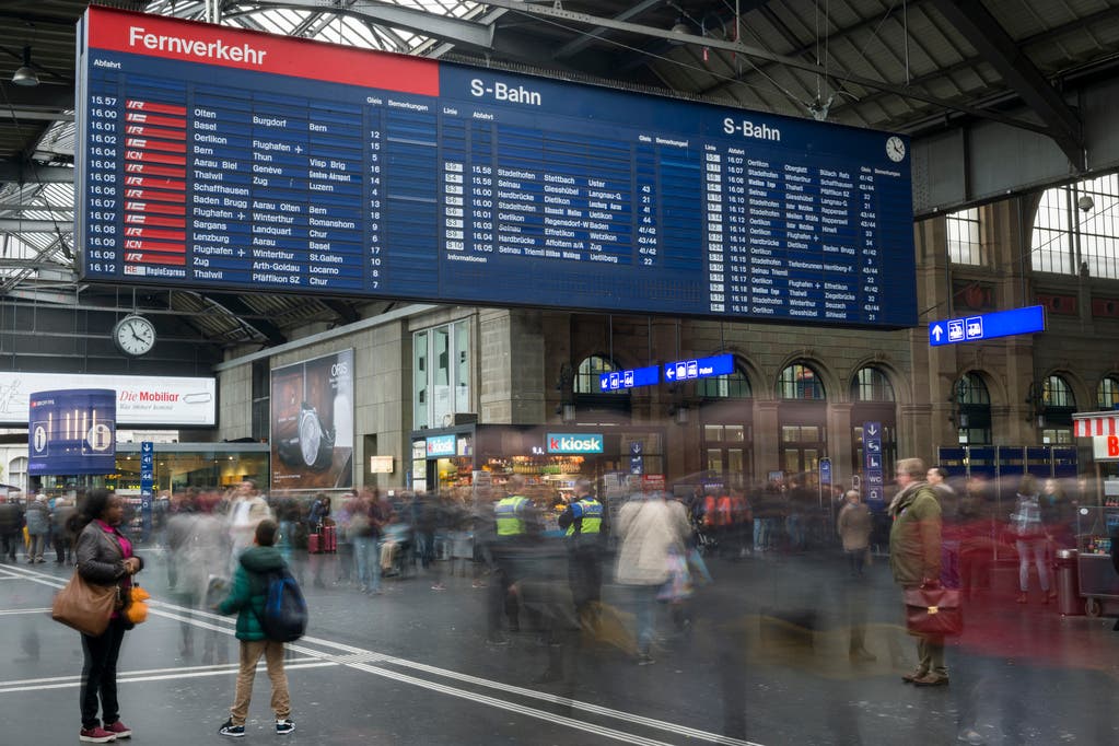 Die mechanische Fallblattanzeige umgeben von Reisenden am Hauptbahnhof in Zuerich