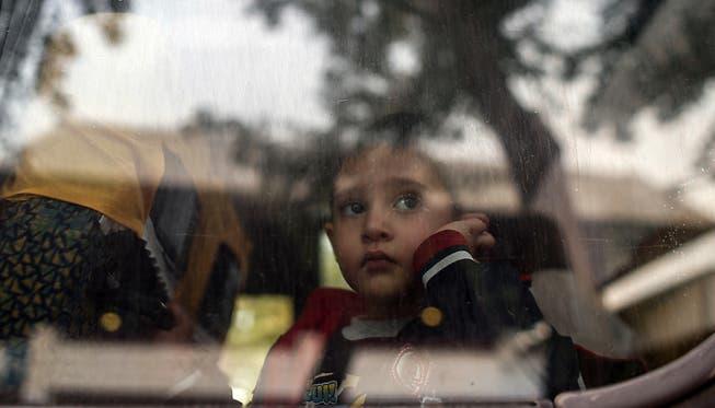 Ein Junge blickt aus dem Fenster eines Buses, der Flüchtlinge transportiert. (Symbolbild)