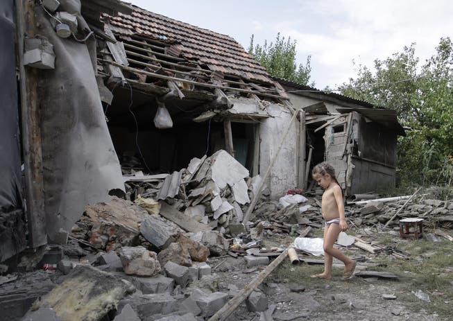 Ein Mädchen vor seinem zerstörten Zuhause in der Region Donezk.