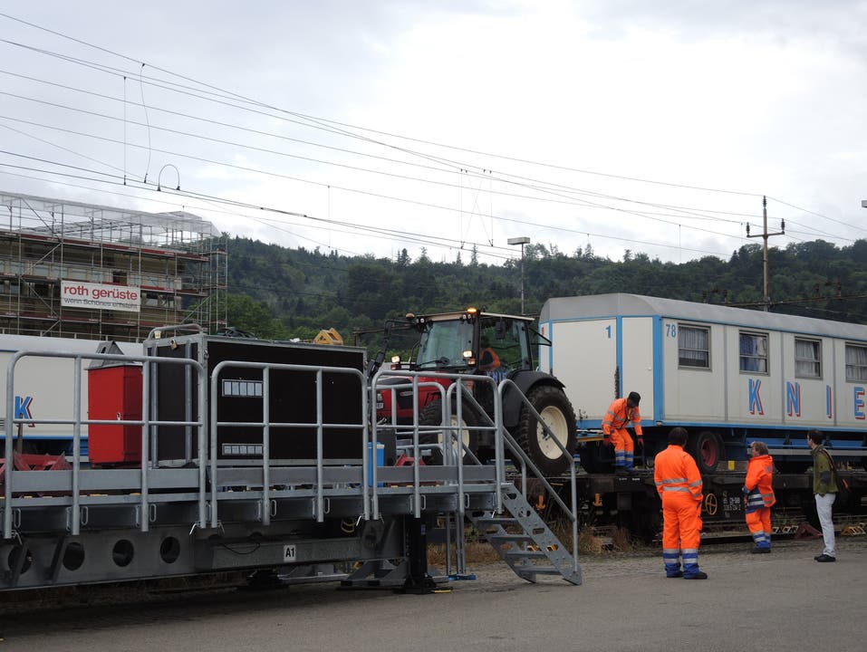 Ein Traktor zieht die Wagen vom Güterzug auf die mobile Rampe