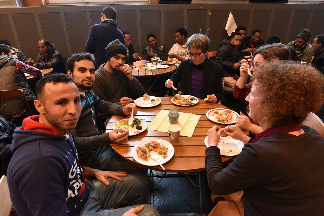  Bewohnerinnen und Bewohner aus Olten und der Region geniessen in der Schützi gemeinsam mit Flüchtlingen Spezialitäten aus deren Herkunftsländern.