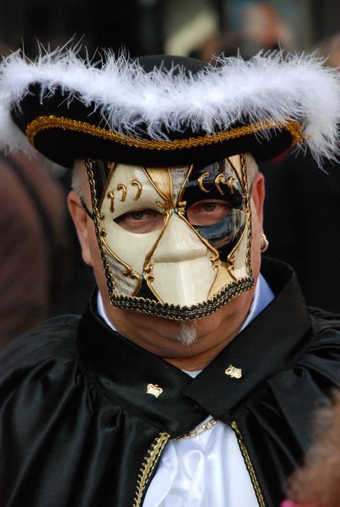 Ein Zaungast mit einer venezianischen Karnevalsmaske.