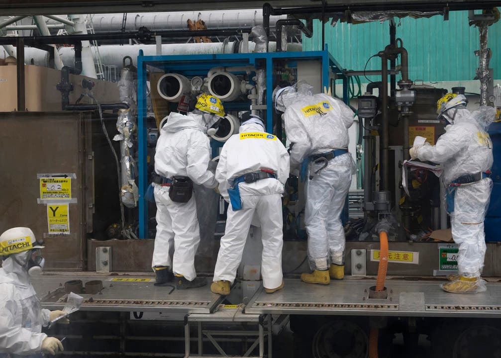 Gut geschützte Arbeiter flicken den vom Tsunami beschädigten Reaktor Fukushima Daichi.