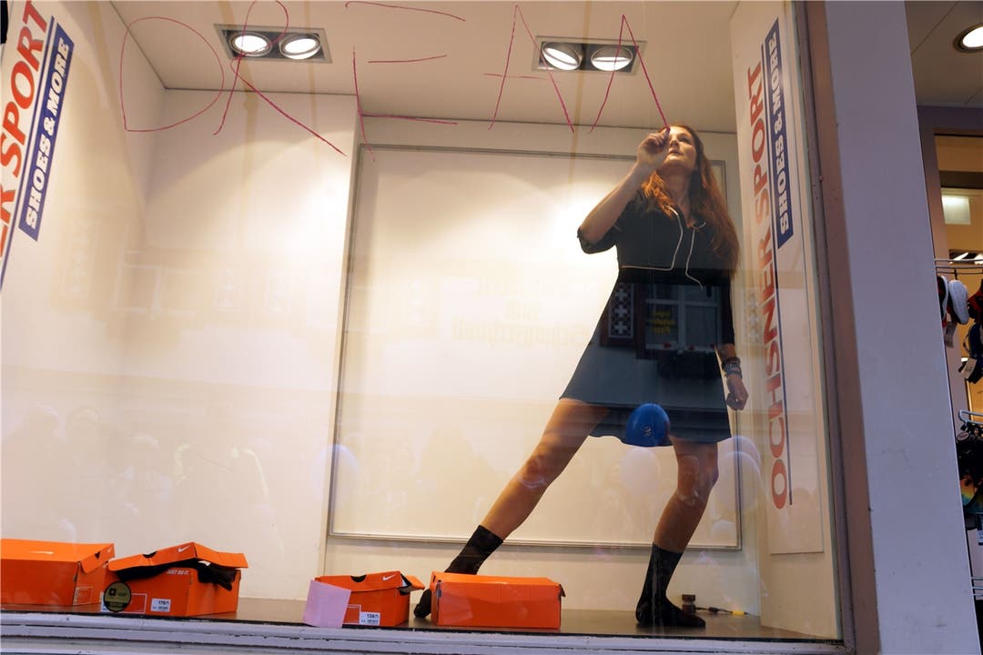 Tänzerin Christina Szegedi schreibt mit Ölkreide das Wort «Dreams» auf das Schaufenster von Ochsner Sport.