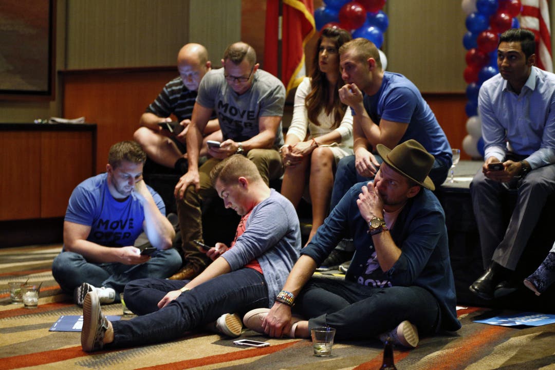 Sie ahnen die Niederlage: Anhänger der Demokraten haben sich an einer Wahlveranstaltung in Dallas auf den Boden gesetzt und starren gebannt auf ihre Smartphones.