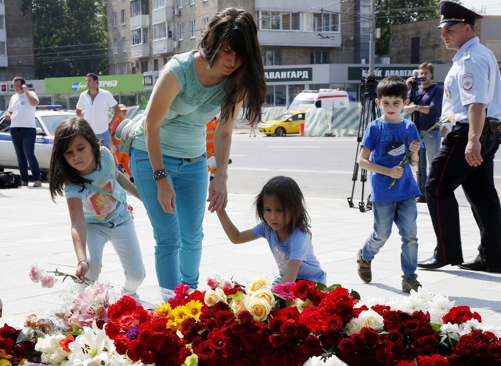 Ein Frau und ihre Tochter legen Blumen nieder - zum Gedenken an die Opfer.