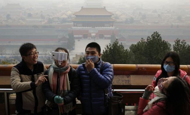 Peking-Besucher schützen sich mit Masken vor dem Smog. Foto: Keystone