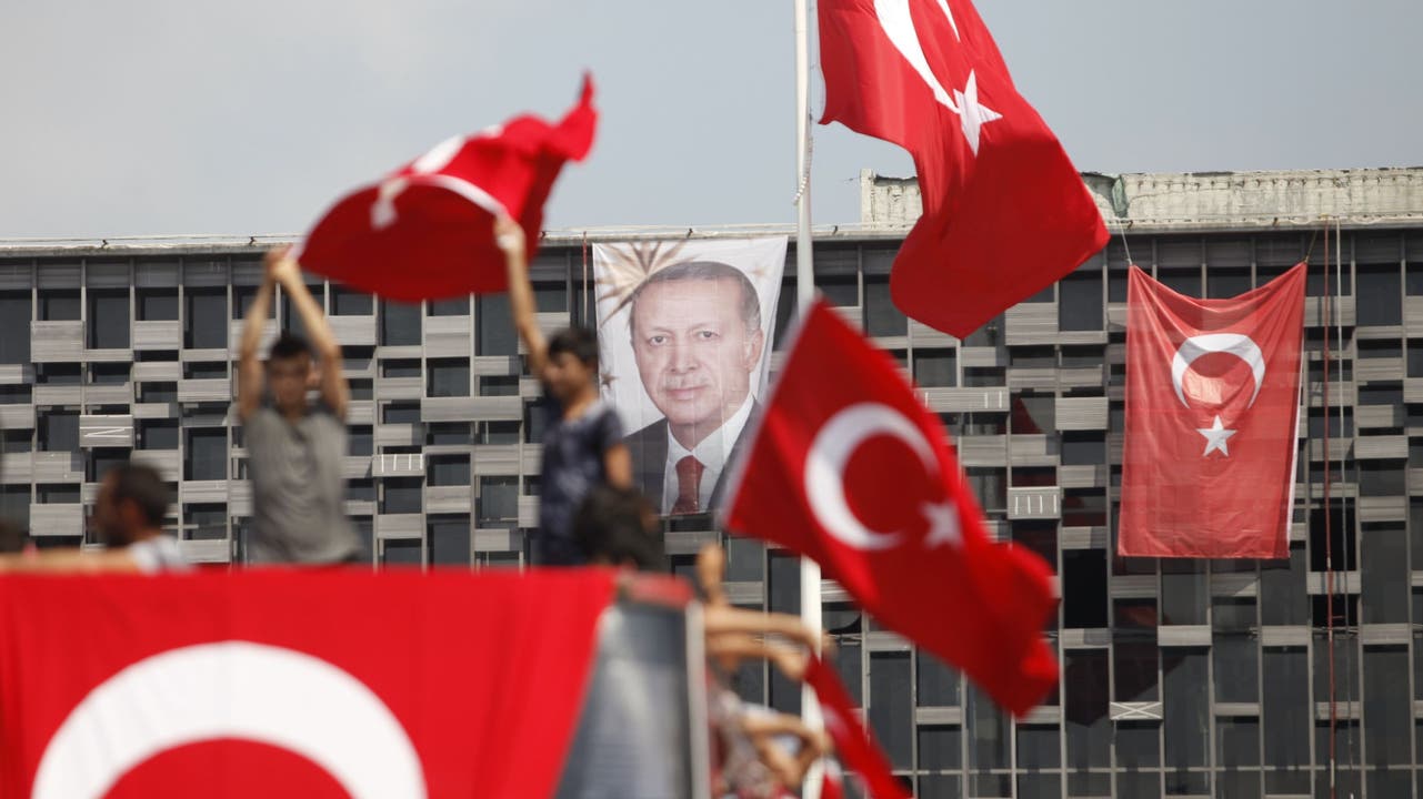 Die Bevölkerung steht hinter Präsident Erdogan An einem Gebäude am Taksim-Platz in Istanbul hängt sein Porträt, davor schwenken Anhänger türkische Flaggen.