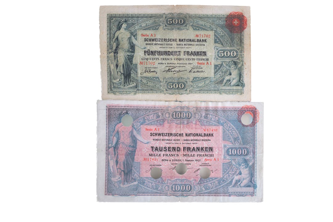 Die 500-Franken-Note war die erste, die die SNB im Jahr 1907 herausgab. Die SNB selbst besitzt sie nicht. Unten die 1000er-Note derselben Serie. Durch die Lochung wurde die Note entwertet.