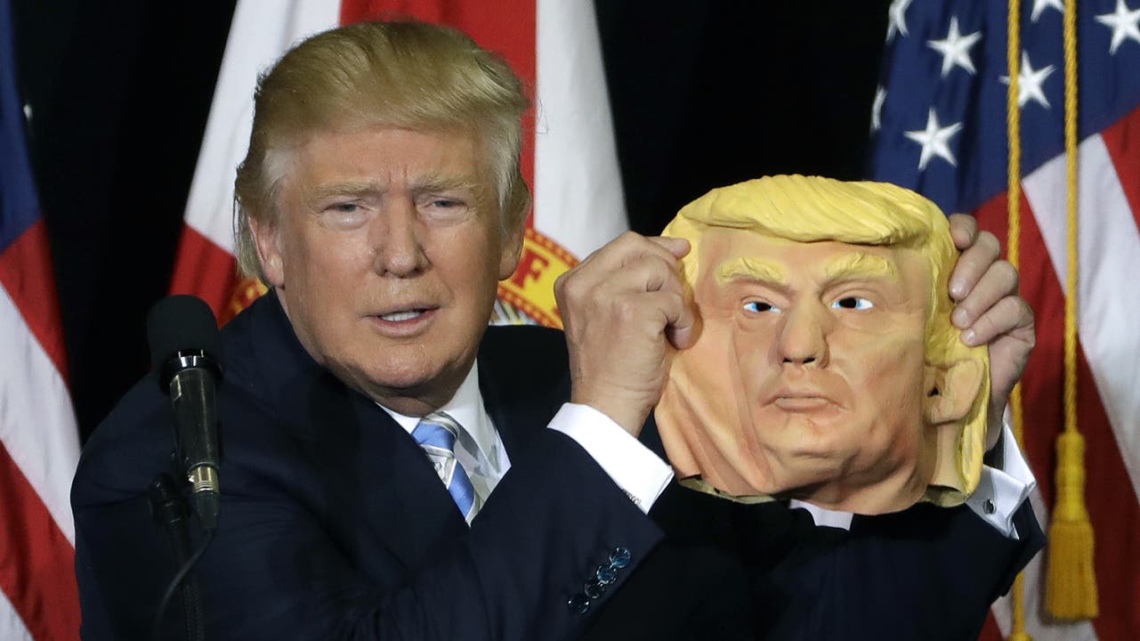 Donald Trump mit einer Maske von seinem Gesicht.