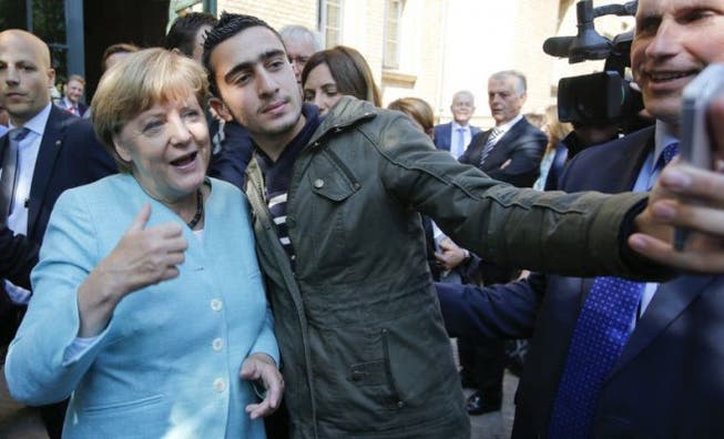 Angela Merkel posiert mit einem Flüchtling: «Weiss sie, was sie tut?», fragen die Medien. Foto: Reuters