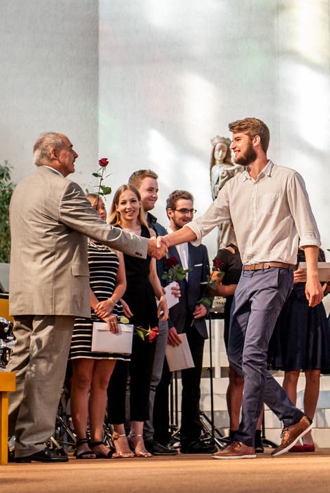 Die Maturandinnen und Maturanden erhalten von Rektor Kurt Wiederkehr eine Rose zum Abschluss.