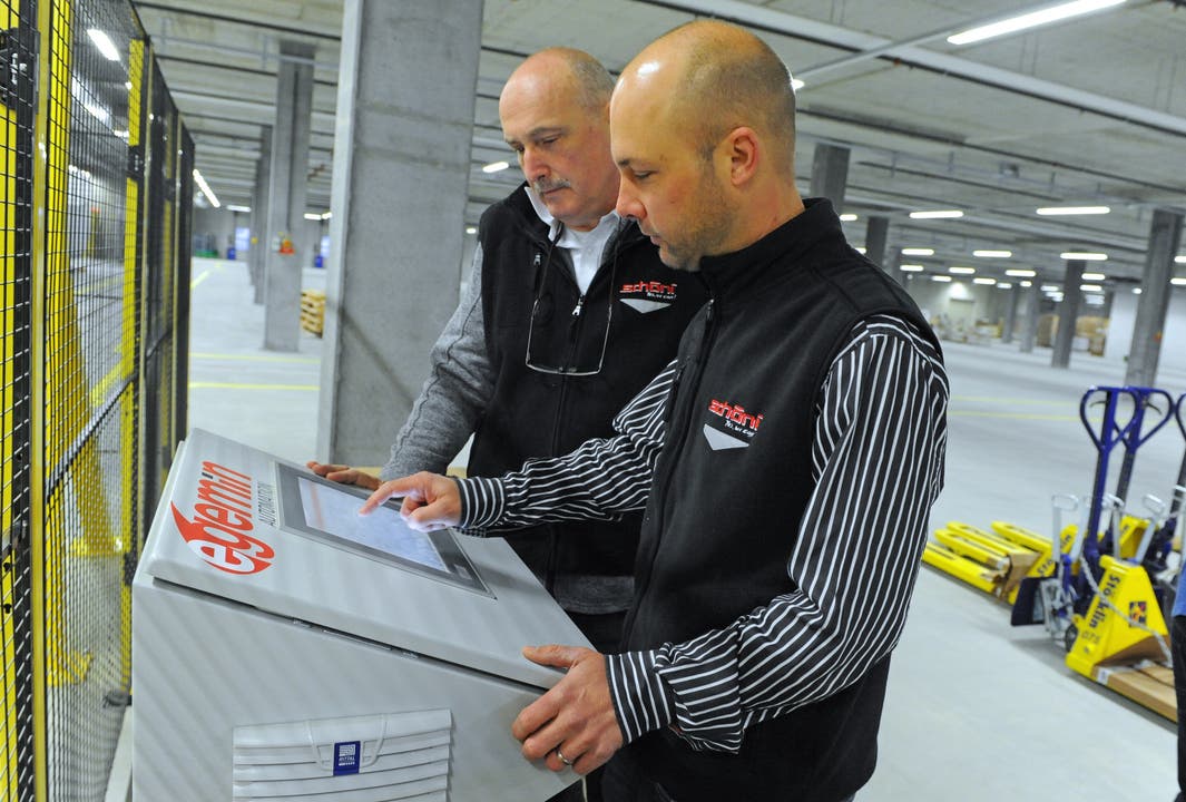 Peter Righi, Leiter Technik (hinten), und Thomas Amsler, Leiter Logistik, kontrollieren die neue Palettenförderanlage mit integriertem Scanner.