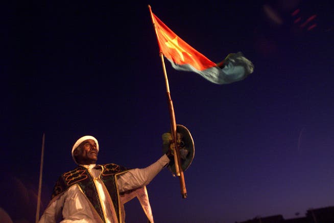 Ein Mann in traditioneller Kleidung schwenkt die eritreische Flagge am Unabhängigkeitstag.