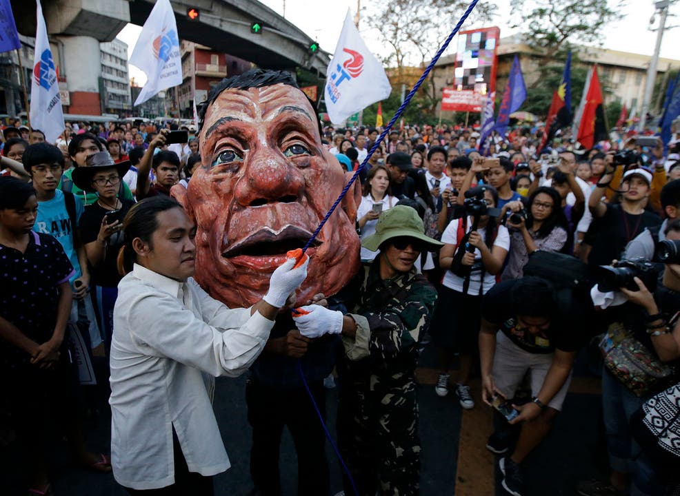 Manila, Philippinen Während einer Kundgebung gehen die Menschen nicht nur für die Rechte der Frau auf die Strasse, sondern auch, um gegen die Wiedereinführung der Todesstrafe zu protestieren. Ein Demonstrant trägt eine grosse Maske des Präsidenten Rodrigo Duterte.