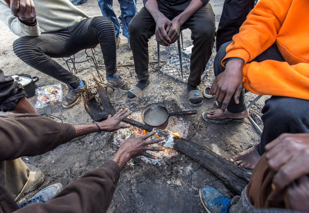 Flüchtlinge wärmen sich an einem Feuer auf