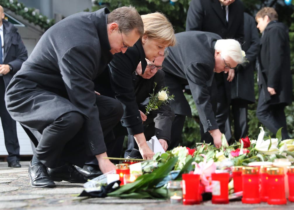 Bundeskanzlerin Angela Merkel und andere legen Blumen nieder.