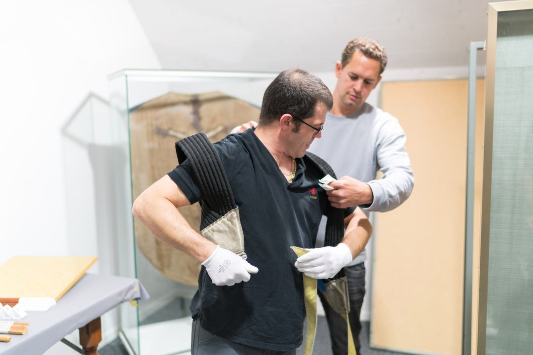 Konservator Thomas Imfeld hilft Museumstechniker Angelo Cirelli beim Überziehen des Traggurtes. Es gibt keinen Lift im Kloster; es bleiben nur Muskelkraft und gute Tragtechnik.