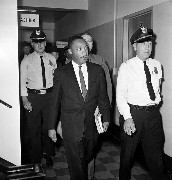 Martin Luther King verlässt das Gericht am 25. Oktober 1960. Er wurde wenige Tage zuvor während eines Sitzstreiks verhaftet und zu vier Monaten Gefängnis verurteilt. Nach drei Tagen wird er auf Intervention von Senator John F. Kennedy und gegen Kaution aus der Haft entlassen.