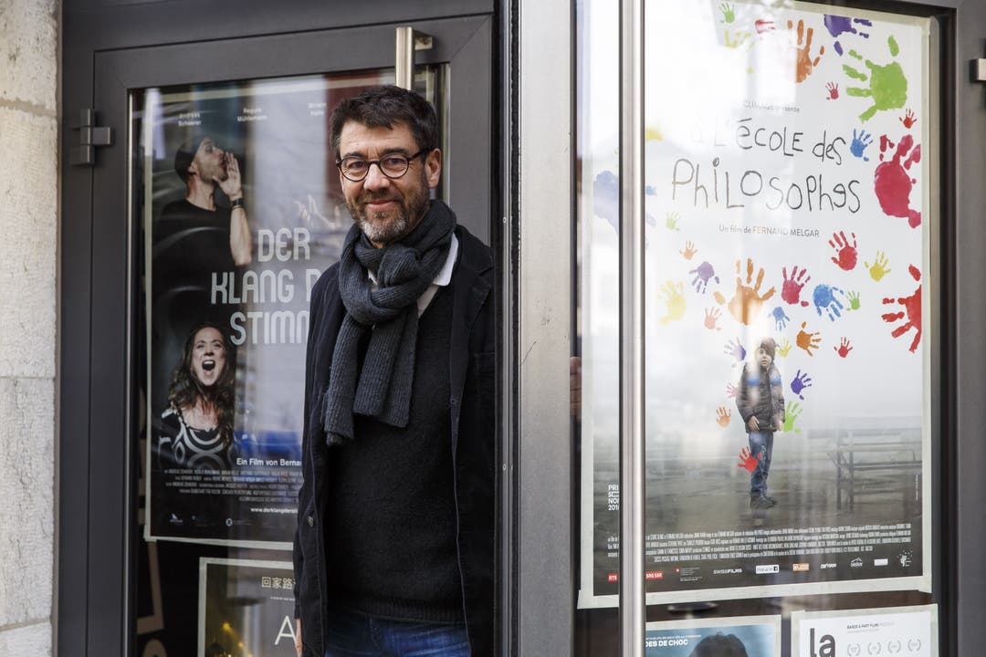 Fernand Melgar posiert vor dem Landhaus mit dem Plakat seines Filmes.
