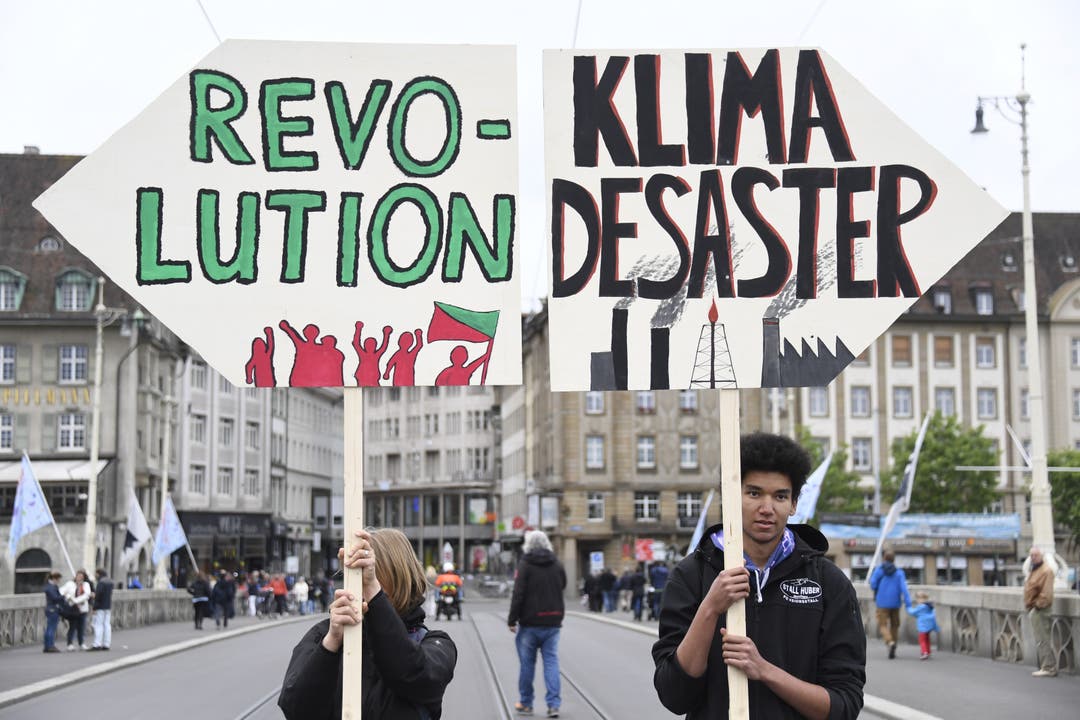 Zwei Demonstranten halten Tafeln mit der Aufschrift «Revolution» und «Klima Desaster» in die Höhe.