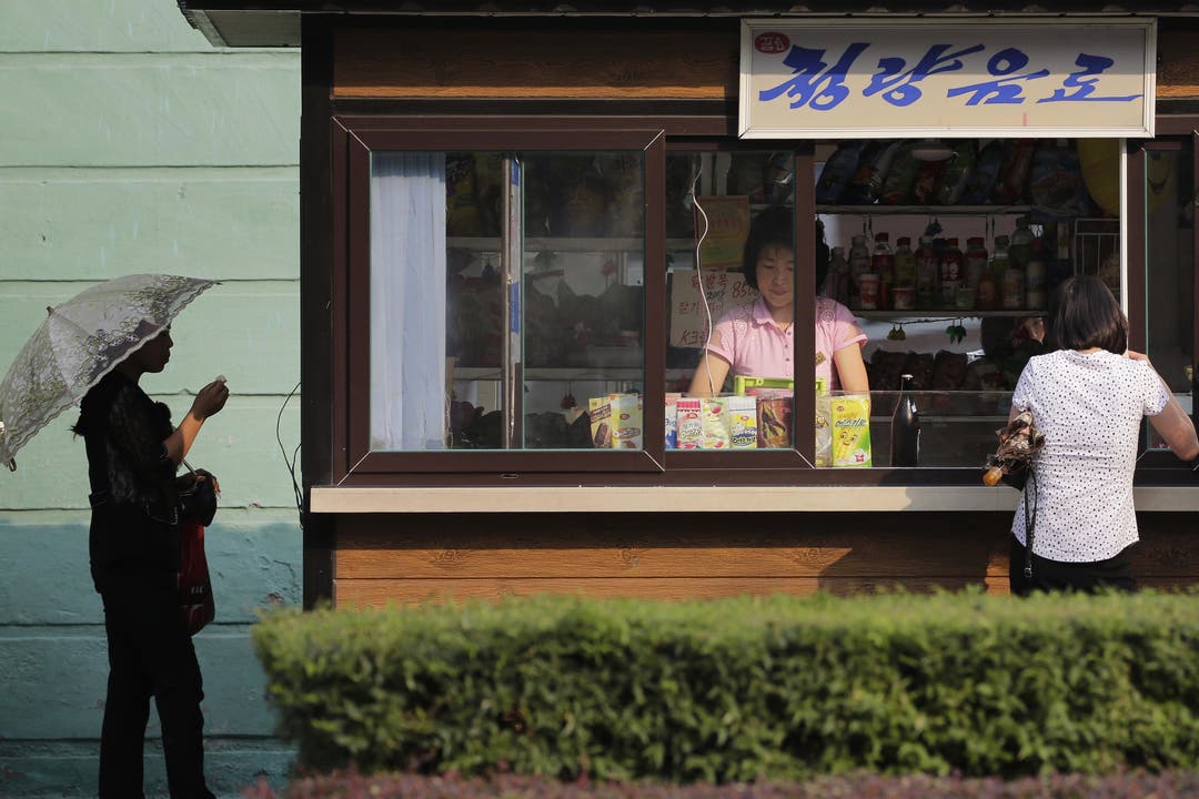 Alltag in Nordkorea - Impressionen Eine Frau steht in einem Kiosk, der Esswaren und Getränke verkauft.