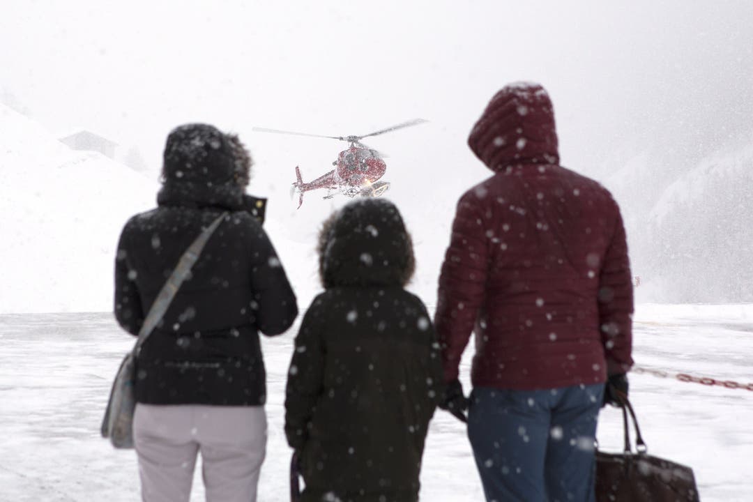 Eine Familie wartet mit ihrem Gepäck auf den Hubschrauber.
