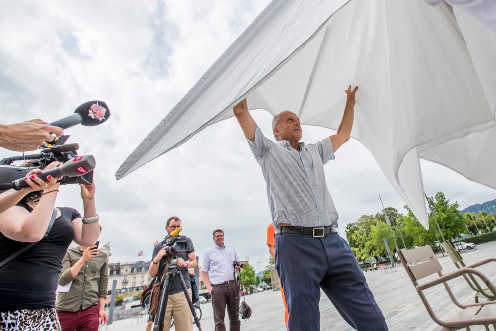 FDP-Stadtrat Filippo Leutenegger öffnet einen von rund 20 Sonnenschirmen, die vorerst zwischen August und September getestet werden.