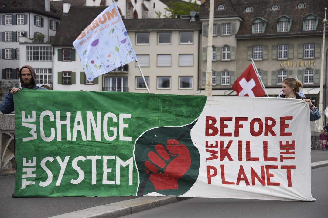 Zwei Demonstranten halten ein Transparent mit der Aufschrift «We change the system – Before we kill the planet»