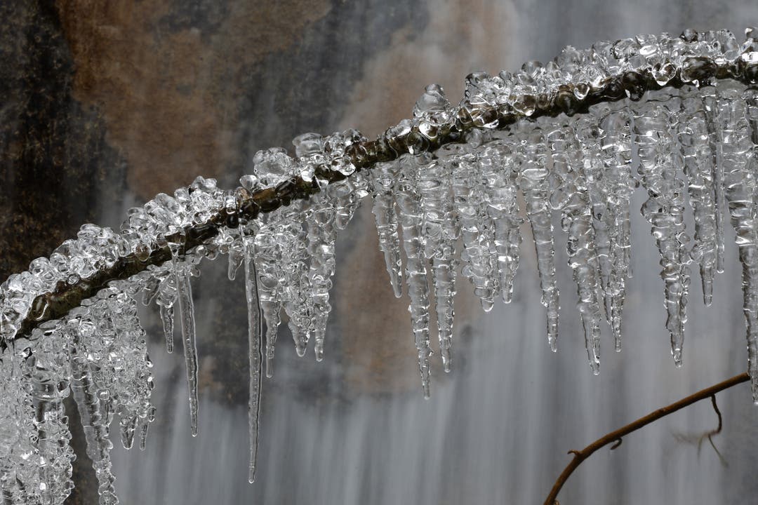 Eiszapfen glitzern wie Diamanten vor einem Wasserfall im oberen Baselbiet.