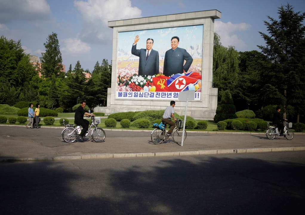 Ein Velofahrer radelt an einem Bild der ehemaligen Führer des Landes, Kim Il-sung und Kim Jong Il, vorbei.