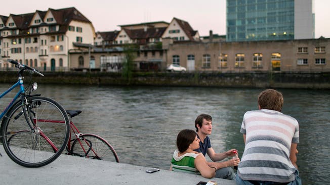 Menschen sitzen am Ufer der Limmat beim Gemeinschaftszentrum Wipkingen in Zürich. (Symbolbild)
