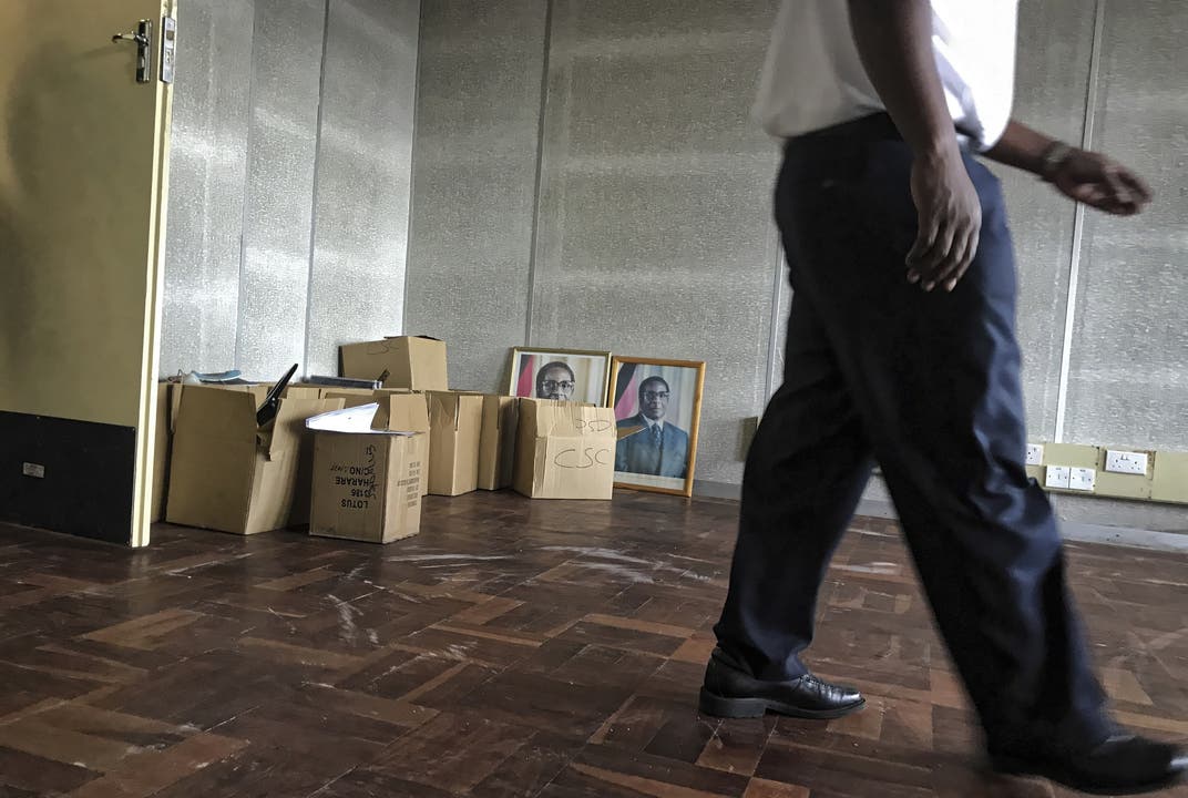 Impressionen aus Simbabwe Ein Arbeiter läuft in einem Regierungsgebäude an Fotografien vom unter Hausarrest stehenden Präsidenten Robert Mugabe vorbei.