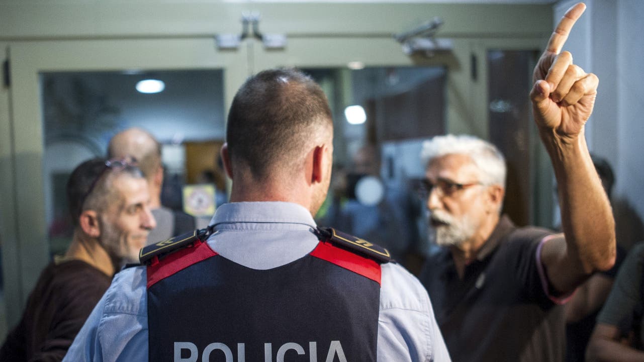 Katalanische Regionalpolizisten teilen einem Rektor mit, dass die Schule geschlossen bleiben muss.