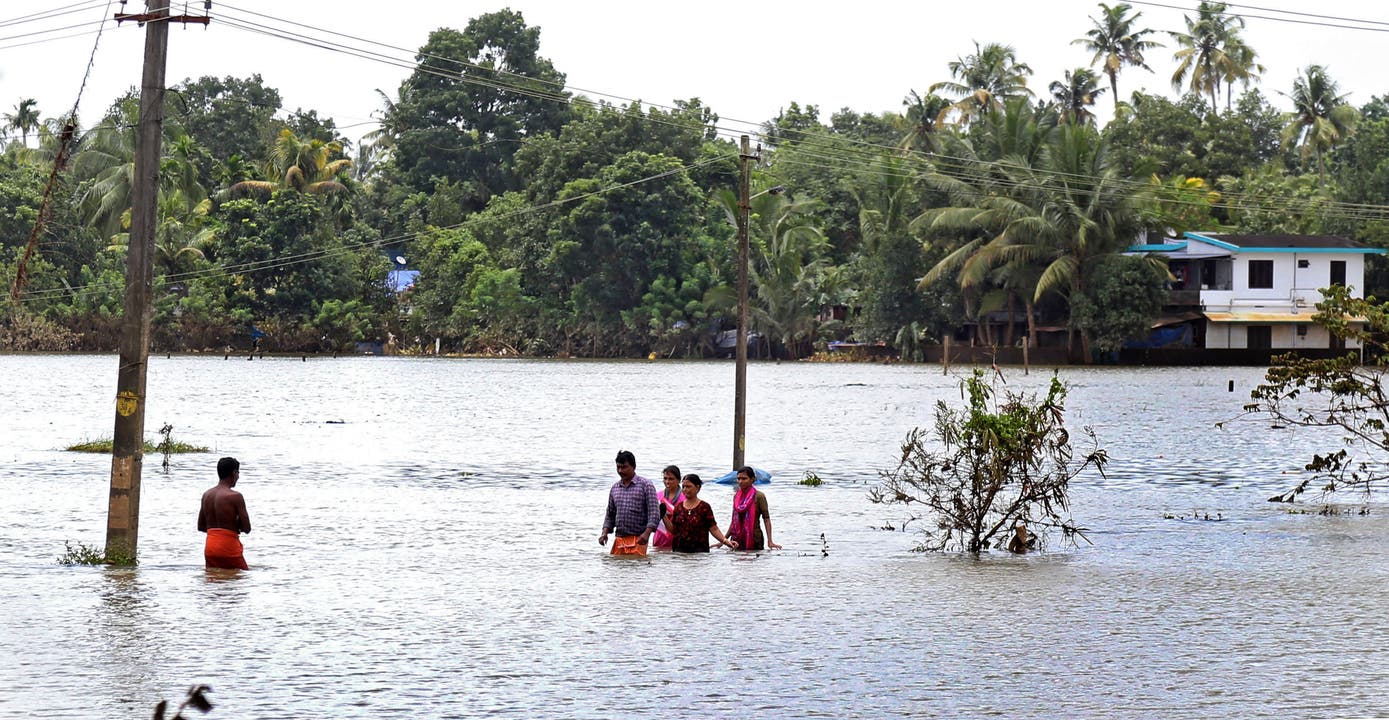 Menschen waten durch überflutete Gebiete