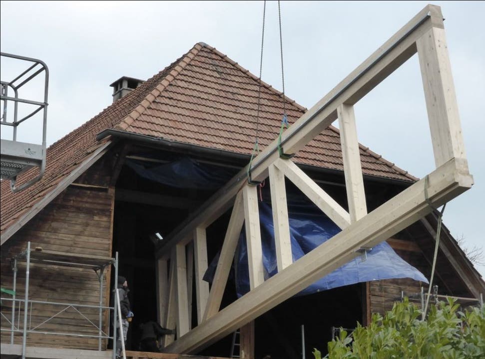 Die Holzkonstruktion unter dem Dach wird mit dem Kran angeliefert