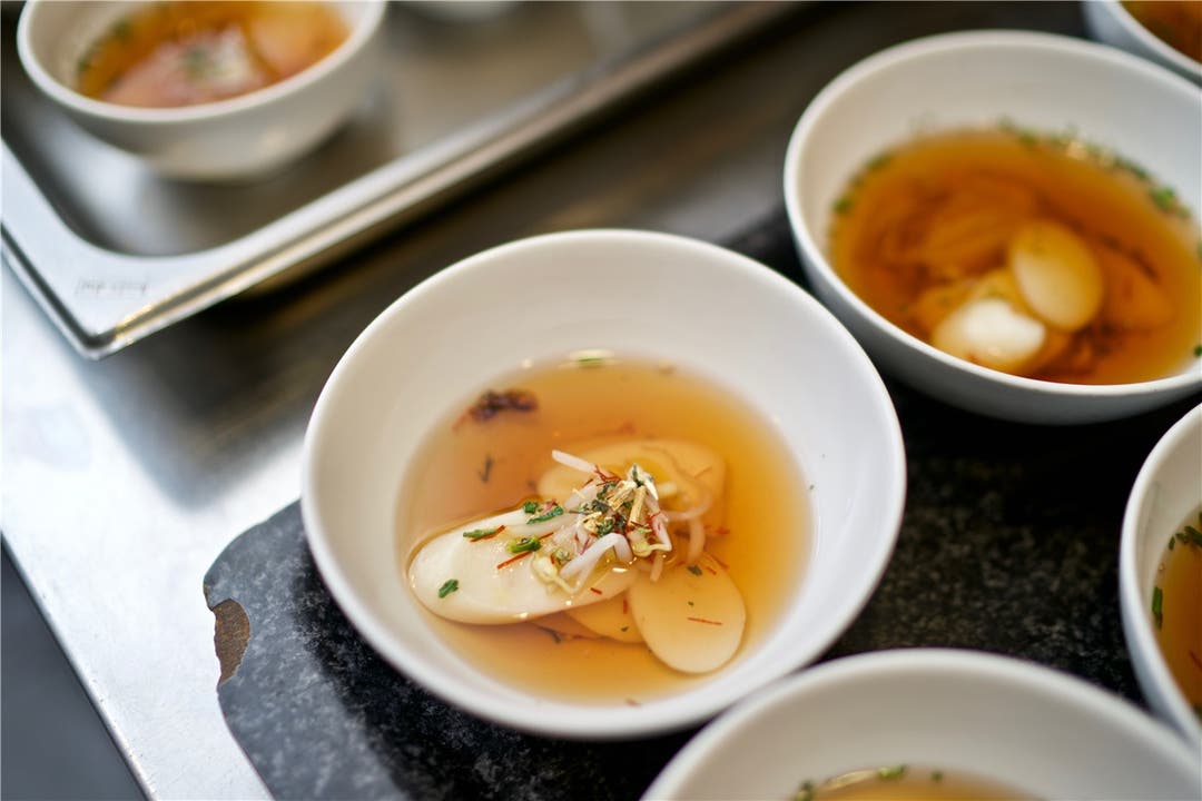 Die Reiskuchensuppe verfeinert Jeong Kwan mit Mungobohnensprossen, Lotusblättern und Peperonifäden.