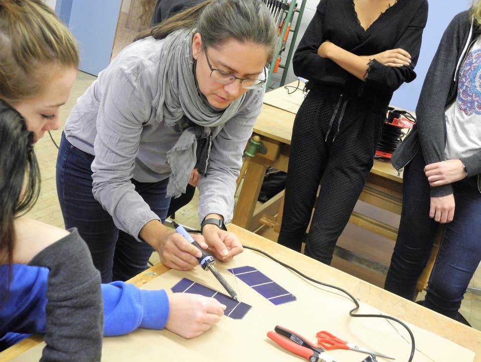  Workshop-Leiterin Thalia Meyer zeigt vor, wie Siliziumscheiben zu einem Photovoltaikmodul gelötet werden.