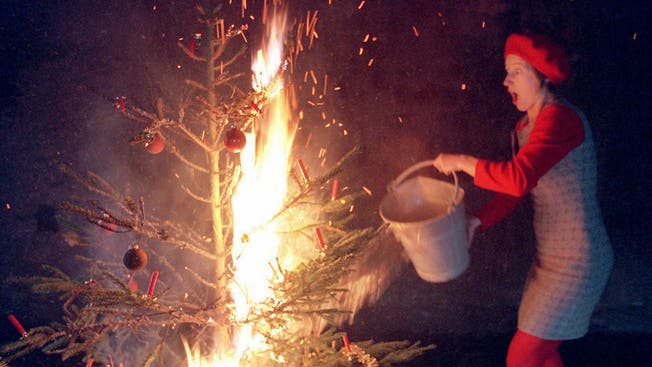 Eine Frau löscht einen brennenden Christbaum. Die Statistik zeigt, dass die Aargauer Polizei im Dezember am meisten Brände meldet.