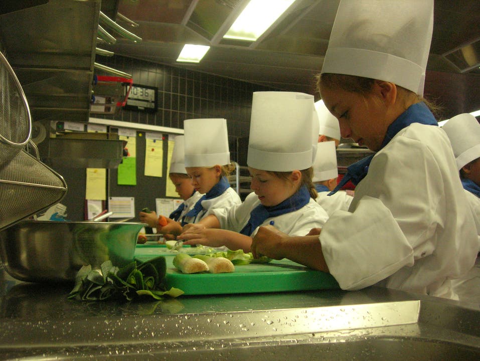  Kinder beim Ferienkurs an der Hotelfachschule Belvoirpark schnetzeln Gemüse für die Lasagne.