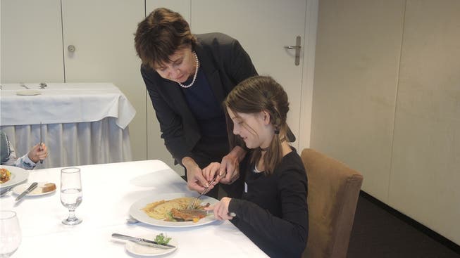 Katrin Künzle, Trainerin für gute Umgangsformen, zeigt der neunjährigen Chanelle, wie sie Messer und Gabel korrekt hält.