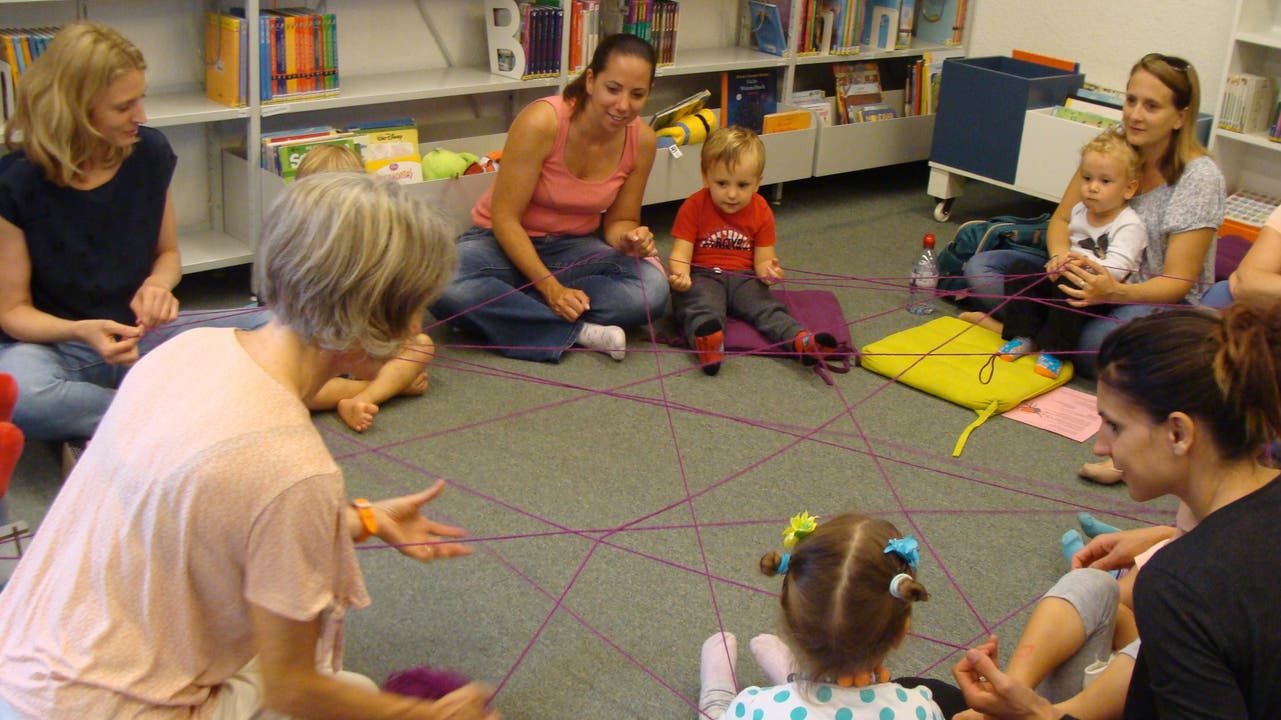 Die Kinder und Mütter verdeutlichen die Geschichte "Die kleine Spinne spinnt und schweigt" mit einem Spinnennetz aus Faden.