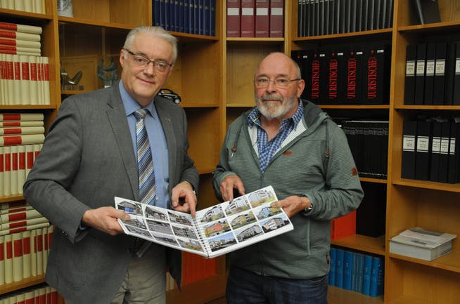 Robert Ramseier (rechts) übergibt das Fotobuch mit allen Gebäuden Wettingens an Gemeindeammann Roland Kuster.