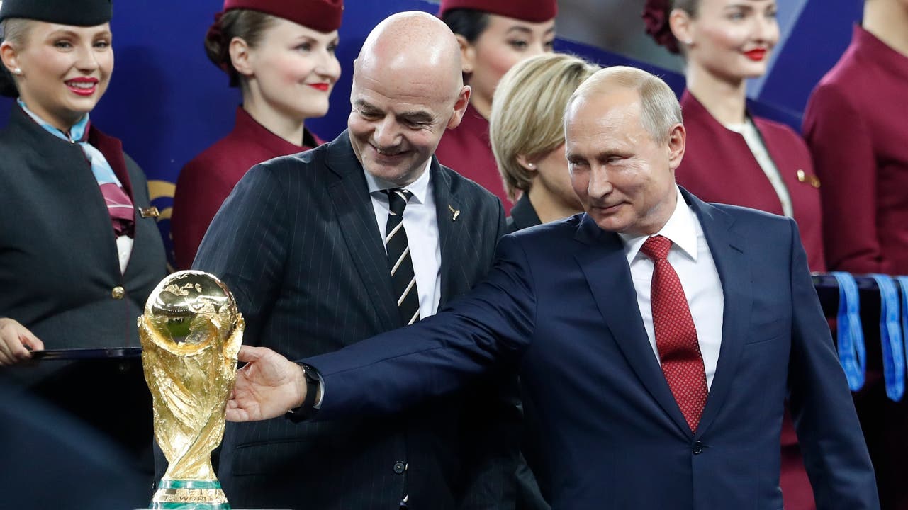 Putin und Gianni Infantino sehen sich den WM-Pokal genau an.