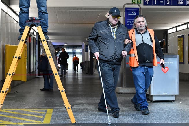 Der sehbehinderte Thomas Biedermann wird von einem SBB-Mitarbeiter um eine Leiter herumgeführt, die in der Martin-Disteli-Unterführung im Weg steht.