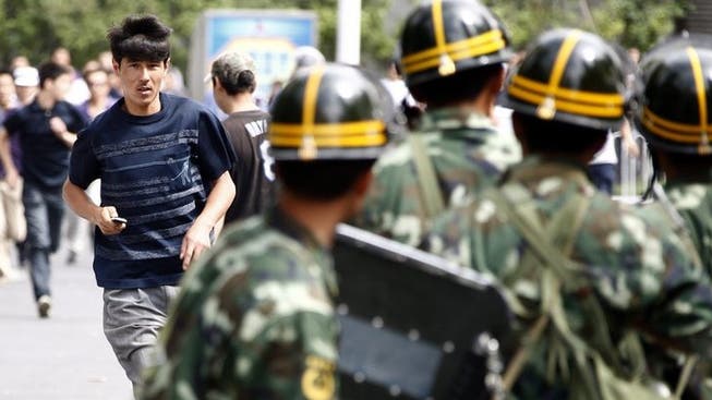 Ein Uigure läuft auf eine Gruppe von chinesischen Sicherheitskräften zu.