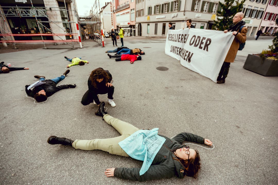 Dabei stellen sich Aktivisten tot auf dem Boden.